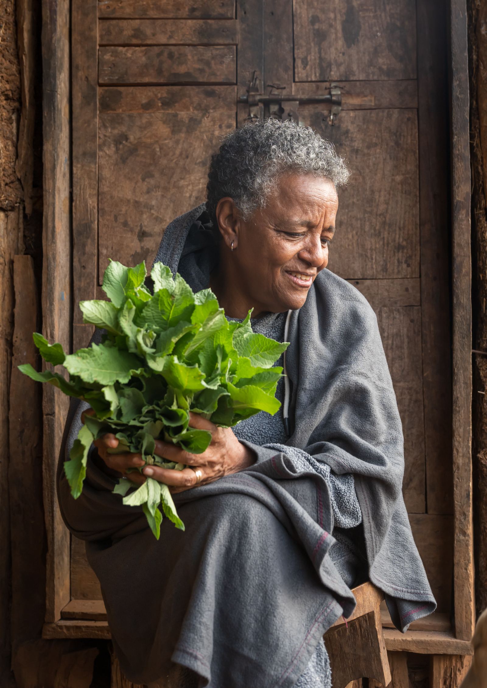 Woman with harvested greens at the farmhouse door